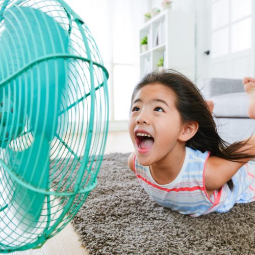 sweet beautiful little children lying down on living room floor and face to electric fan enjoying cool wind with flying posing with selective focus photo.